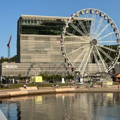 Widok na nowoczesny budynek Muzeum Narodowego w Oslo z charakterystycznym napisem "MUNCH" i diabelskim młynem w tle.