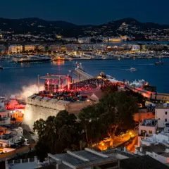 Concerto sul bastione di Dalt Vila, Ibiza, con la baia illuminata e le luci della città. Un evento indimenticabile per chi ama la musica e la magia di IMS Ibiza.