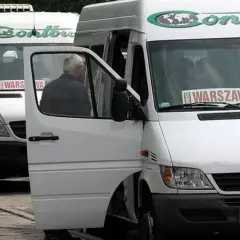 Białe busy Contbus z napisem "WARSZAWA" na przedniej szybie, jeden z otwartymi drzwiami.
