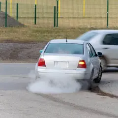 Srebrny samochód z dieslem wydala biały, śmierdzący dym z rury wydechowej, zanieczyszczając powietrze.