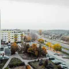 Widok na osiedle z blokami mieszkalnymi i drogą. Jesienne drzewa dodają koloru. Czy mieszkania potanieją?