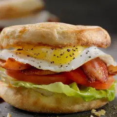 Pyszna oferta śniadaniowa McDonald's: bułka z jajkiem sadzonym, chrupiącym boczkiem, pomidorem i sałatą. Idealny początek dnia!