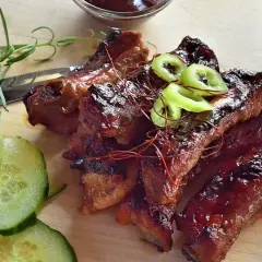 Délicieux ribs barbecue, prêts à déguster. Le temps de cuisson parfait pour des ribs tendres et savoureux. Accompagnés de concombre frais et de romarin.