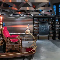 Máquina del tiempo inspirada en H. G. Wells, con asiento de terciopelo rojo y detalles dorados, lista para viajar.