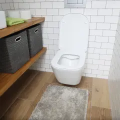 Nowoczesna łazienka z podwieszanym WC. Obok półka z koszami, ręcznikiem i papierem toaletowym. Widać, ile miejsca na wc podwieszane zajmuje.