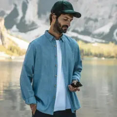 Un homme porte une chemise bleue décontractée, dont la matière légère est parfaite pour une journée au bord du lac.