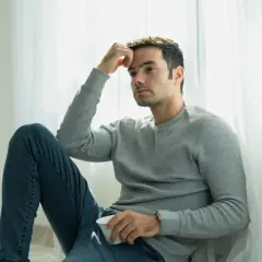 Mężczyzna siedzi przy oknie, zamyślony, trzymając filiżankę. Może to być moment, jak dać facetowi do myślenia.