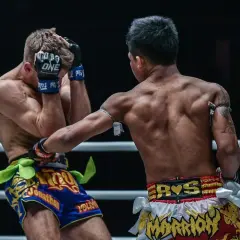 A Muay Thai fighter lands a powerful uppercut, connecting with his opponent's chin. The shovel hook defense is too late.