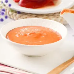 Un cuenco blanco lleno de cremosa salsa de pimientos del piquillo, lista para acompañar tus platos.