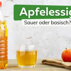 Apfelessig: sauer oder basisch? Eine Flasche und ein Glas mit goldgelbem Apfelessig stehen neben einem roten Apfel.