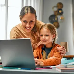 Mama pomaga córce w nauce online, wspólnie wypełniają wniosek o opiekę nad dzieckiem.