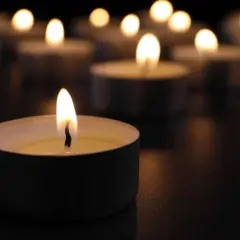 Płonące świece w mroku, symbolizujące żałobę i pamięć.