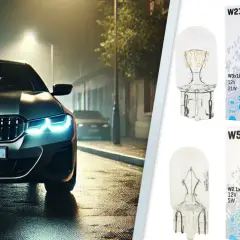 Srebrne BMW z włączonymi światłami pozycyjnymi na mokrej ulicy nocą. Obok żarówki Vision W21W, W16W, W5W, H6W.