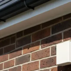 Boîtier blanc fixé sur un mur de briques, sous une gouttière. Peut-être lié à un problème sonde extérieure chaudière.