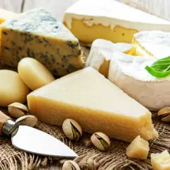 Un assortiment de fromages, dont du bleu et du brie, avec des pistaches. Le fromage est-il une protéine ? Oui, c'est une excellente source.