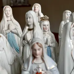 Eine Sammlung von Marienfiguren, die an das maria geburt datum erinnern. Die Figuren tragen weiße Gewänder und einige haben Kronen.