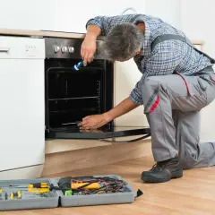 Un technicien effectue le branchement d'un four encastrable, outils à portée de main.