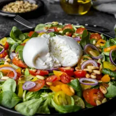 Frischer Salat mit cremiger Burrata, Tomaten, Zwiebeln und Pinienkernen. Perfekt für eine leichte Mahlzeit, auch in der Schwangerschaft.