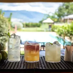 Tre cocktail rinfrescanti con limoni e lime, pronti per una serata figa in un disco pub con vista piscina.