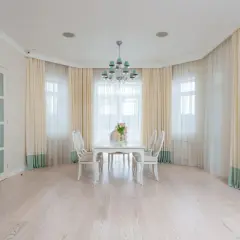 Eleganckie firanki w wykuszu dodają uroku wnętrzu. Jasne zasłony pięknie komponują się z białymi meblami i jasną podłogą.