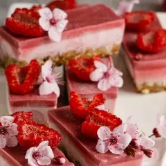 Różowe deserki owocowe z malinami i kwiatami wiśni na białej tacy. Pyszne, zdrowe słodkości.