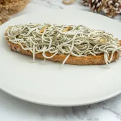 Tosta con gulas al ajillo, un clásico de las recetas con gulas, servida en plato blanco.