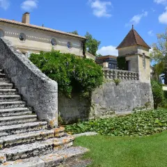 Escalier de pierre menant à un château, avec un étang de nénuphars. Une belle journée pour une visite château Pomerol.