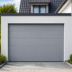 Modernes graues Garagentor einbauen, um Sicherheit und Stil zu vereinen. Gepflasterte Einfahrt und gepflegte Grünflächen umrahmen das Tor.
