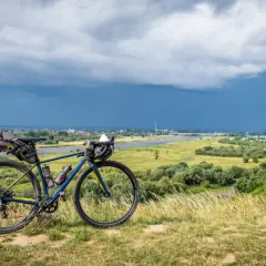 Rower gravelowy z sakwami na tle burzowego nieba nad Wisłą. Przygotowany na wyprawę Wisła 1200.