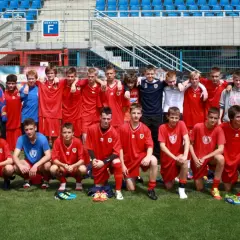 Piast Gliwice zawodnicy w czerwonych strojach pozują do zdjęcia na boisku.