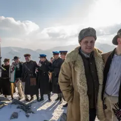 Grupa ludzi w strojach historycznych na tle gór. Czerwona flaga powiewa na wietrze. To może być scena z filmu, która zasługuje na biała odwaga recenzja.