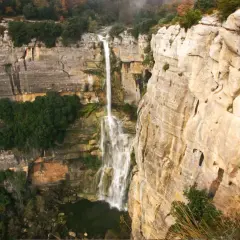 El imponente salt de Sallent cae desde lo alto de acantilados rocosos, rodeado de vegetación exuberante y un paisaje natural impresionante.