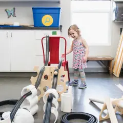 Niña interactúa con un proyecto STEAM de primaria, construyendo una rampa con tubos y madera.