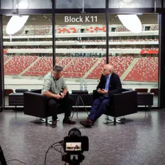 Tomasz Tomaszewski rozmawia z mężczyzną na tle stadionu.