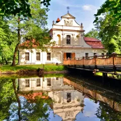 Pałac z mostkiem i odbiciem w wodzie. Wspaniałe zwierzyniec atrakcje czekają na zwiedzających w otoczeniu zieleni.