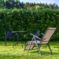 Zielony żywopłot tworzy naturalną barierę, idealną, by tanio odgrodzić się od sąsiada. Stolik i krzesła zapraszają do relaksu.