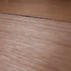 Szczelina na blacie kuchennym wymaga naprawy. Widoczne drewniane słoje sugerują potrzebę renowacji.