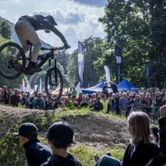 Mountainbiker springt bei einer Veranstaltung in Heubach heute über eine Schanze, während eine Menge zuschaut.