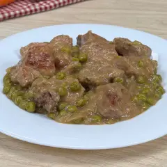 Un saporito spezzatino con piselli, servito su un piatto bianco, pronto per essere gustato.