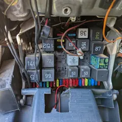 Widok na skrzynkę bezpieczników i przekaźników w samochodzie. Widać bezpiecznik od kierunkowskazu, oznaczenie 18, oraz inne elementy instalacji elektrycznej.