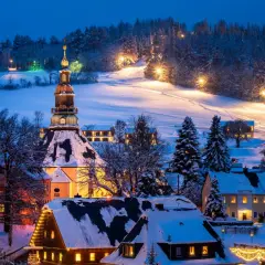 Ein verschneites Dorf in Deutschland, beleuchtet von warmem Licht. Perfekt für einen romantischen Winterurlaub.