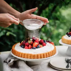 Ein sommerlicher Kuchen mit frischen Beeren wird mit Puderzucker bestäubt.