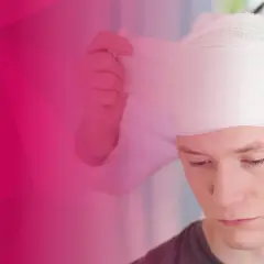 Młody mężczyzna przechodzi bandażowanie głowy przez lekarza.