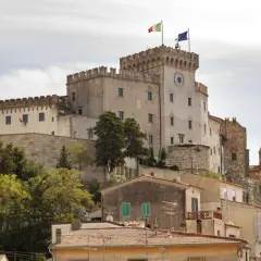Castello Pasquini domina il paesaggio di Rosignano Marittimo, con le sue torri merlate e le bandiere che sventolano al vento.