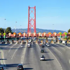 Korkociąg samochodów na autostradach Portugalii, zbliżających się do bramki opłat pod czerwonym mostem.
