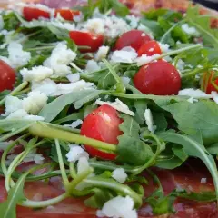 Pizza z rukolą, pomidorkami i parmezanem. Rukola właściwości zdrowotne dodają jej lekkości i świeżości.