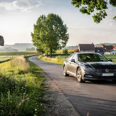 En bil på en slingrande väg i Europa, på väg mot en idyllisk by. Perfekt för en roadtrip Europa.