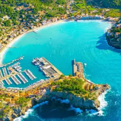 Vacker vy över en turkos bukt med en hamn full av båtar och en stad som klättrar uppför kullarna. En drömsemester i Palma de Mallorca.
