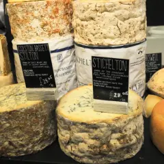 Gros plans sur des fromages anglais, dont le Stilton Colston Bassett et le Stichelton, avec leurs étiquettes de prix.