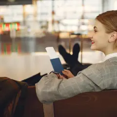Kobieta z paszportem w ręku zastanawia się, czy do Dubaju potrzebny jest paszport. Czeka na lotnisku.